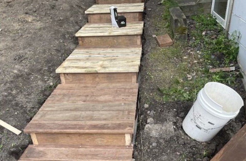 Wooden hillside steps being built beside a home