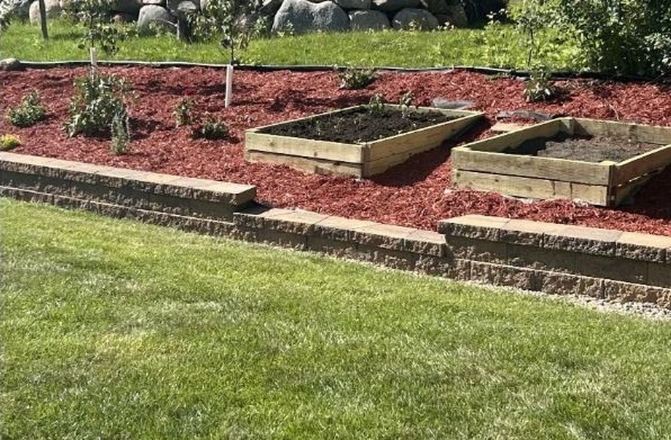 Retaining wall, raised garden beds, and fresh mulch in a backyard